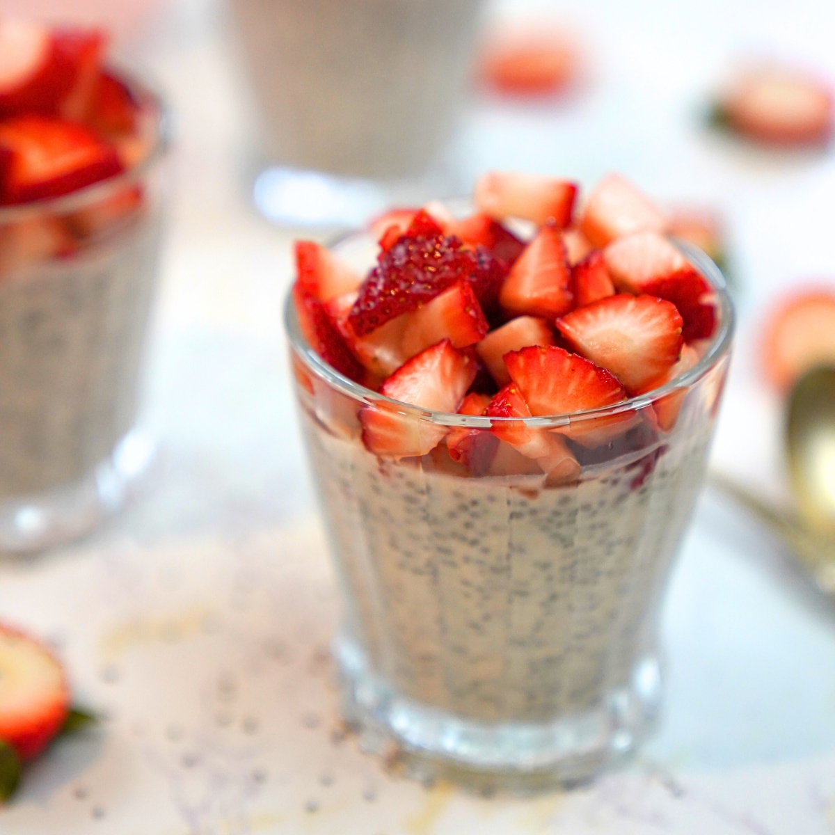 strawberry yogurt chia pudding with fresh strawberry topping in a glass cup