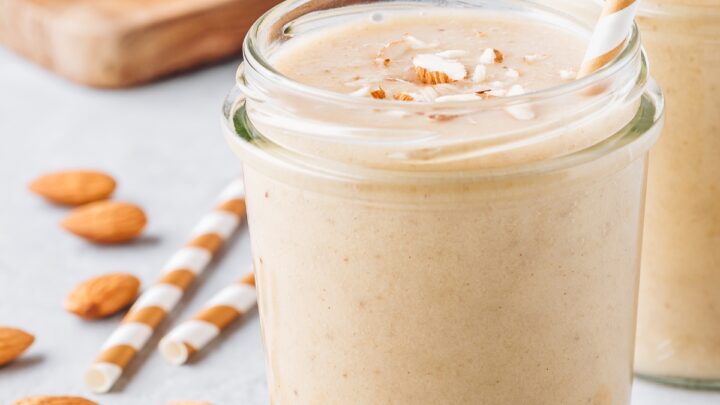 banana almond smoothie in a glass jar with a straw