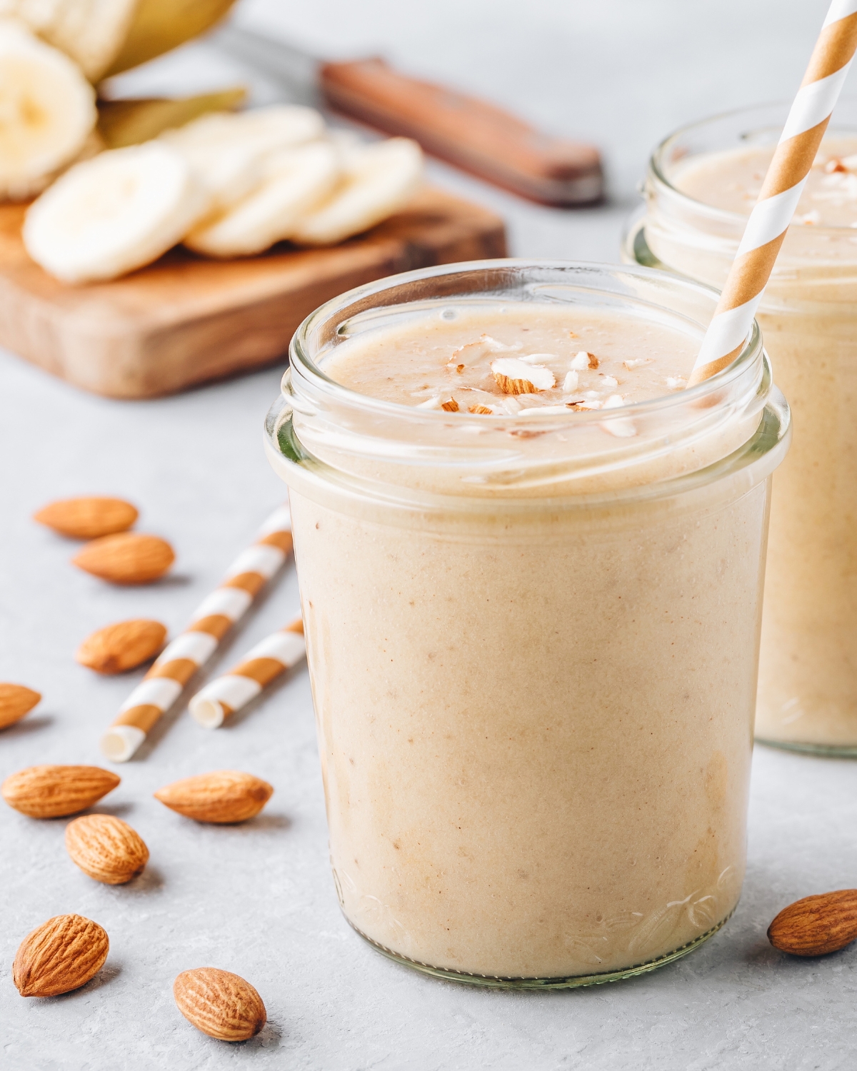 banana almond smoothie in a glass jar with a straw