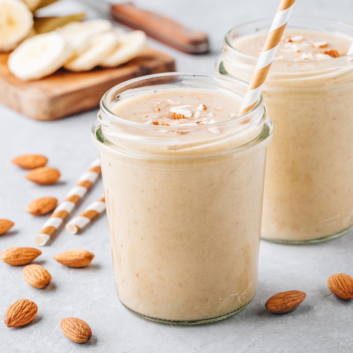 banana almond smoothie in a glass jar with a straw