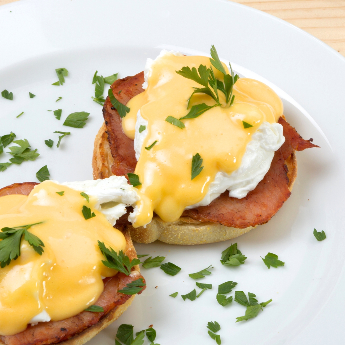 Easy Eggs Benedict - poached eggs with bacon and hollandaise sauce on a white plate