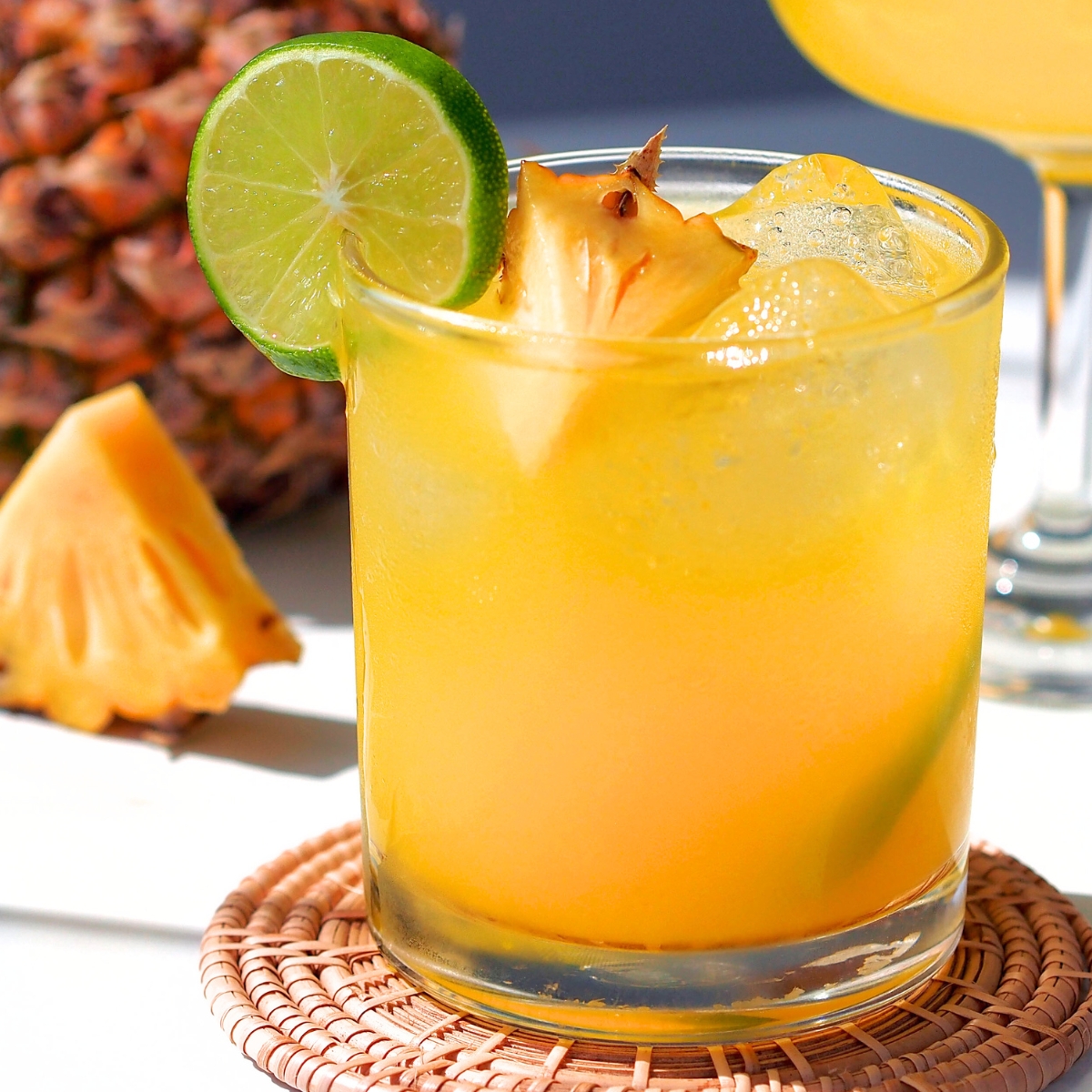 pineapple apricot mocktail in a short glass with lime and pineapple garnish