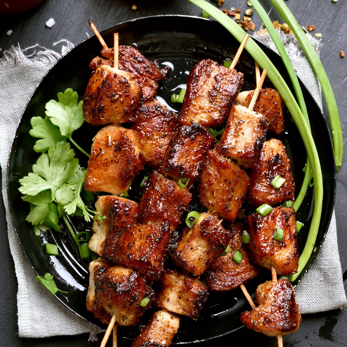 Filipino BBQ pork skewers on a black plate