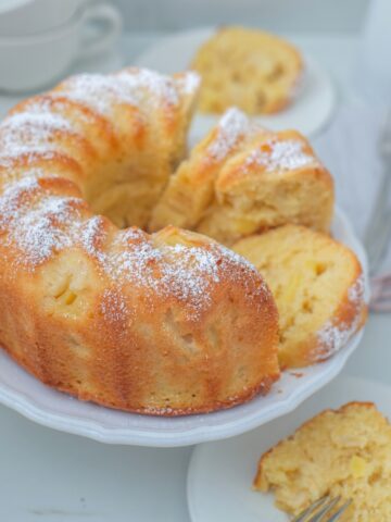 pineapple bundt cake on a white cake stand with a gray background