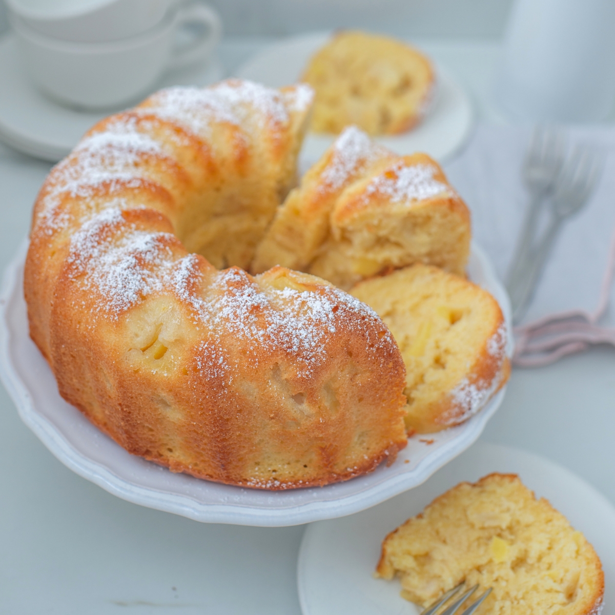 pineapple bundt cake on a white cake stand with a gray background