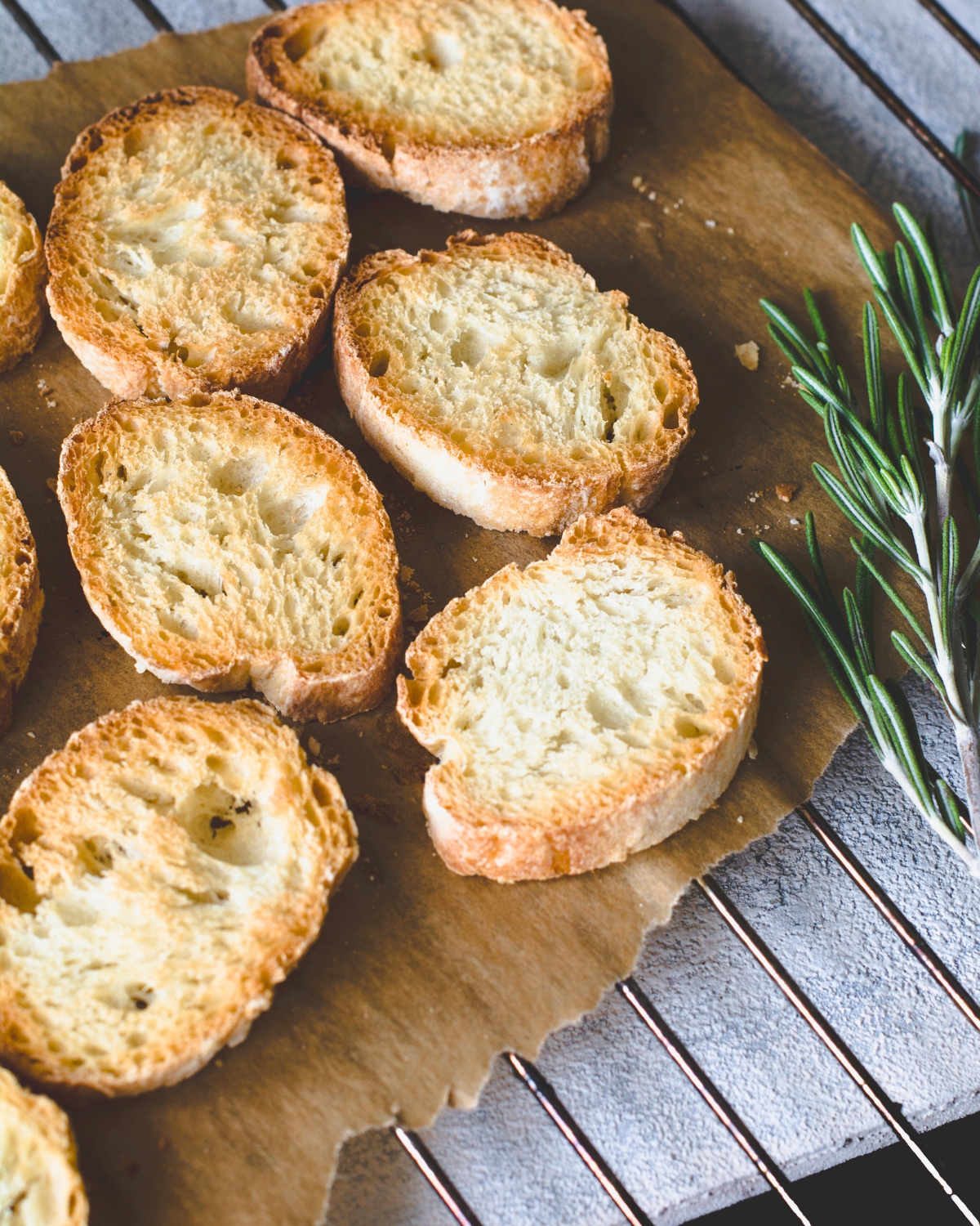 How to Make Crostini - toasted bread slices on a wooden board with rosemary 