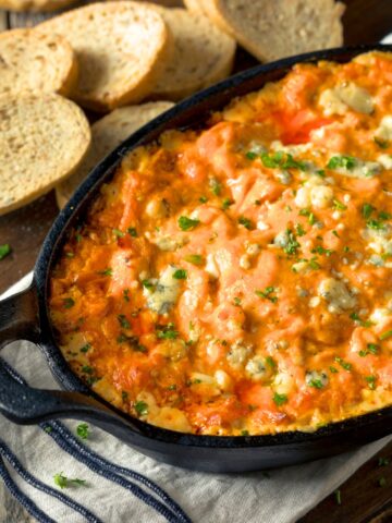 Baked Buffalo Chicken Dip in a black pan with toasted bread slices