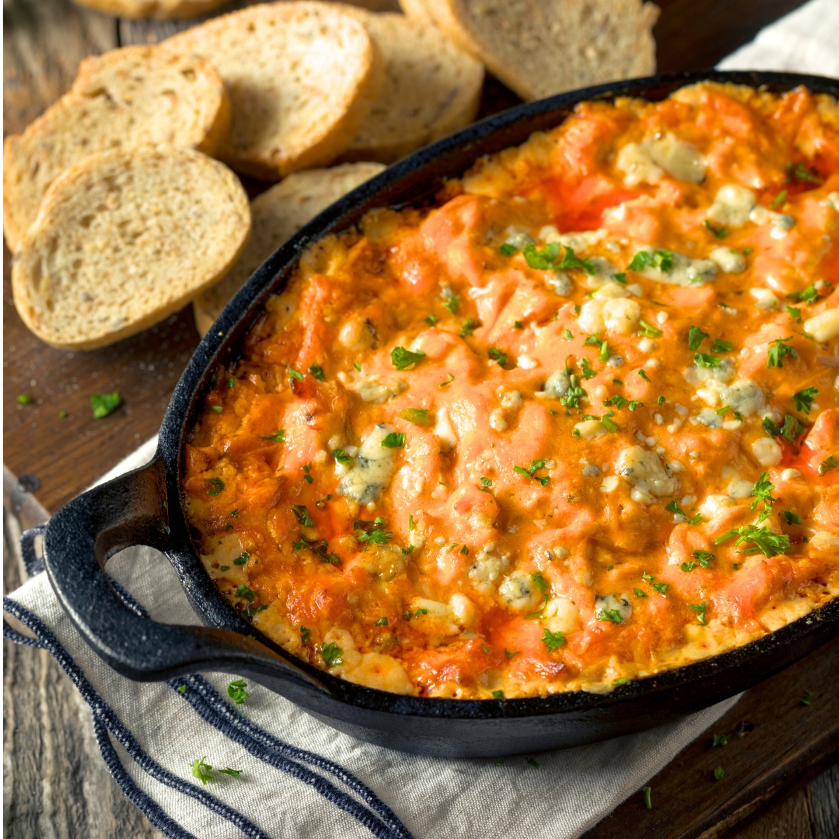 Baked Buffalo Chicken Dip in a black pan with toasted bread slices