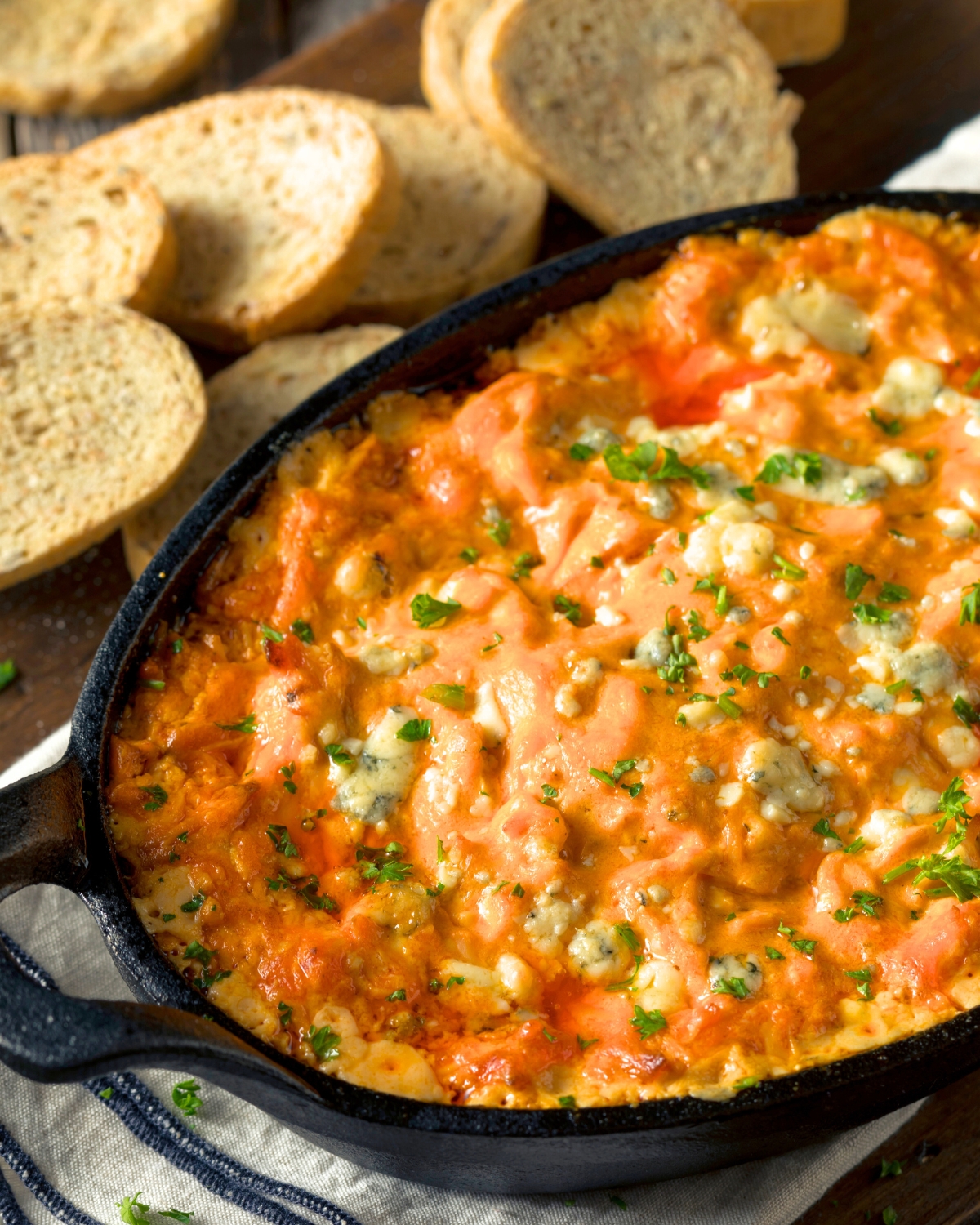 Baked Buffalo Chicken Dip in a black pan with toasted bread slices