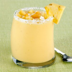 Coconut Mango Pineapple Smoothie with a green background