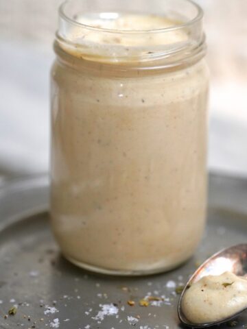 Creamy Apricot Tahini Dressing in a glass jar with a spoon