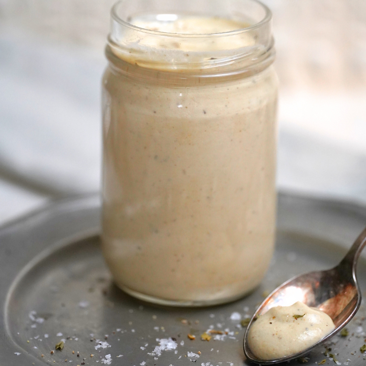 Creamy Apricot Tahini Dressing in a glass jar with a spoon