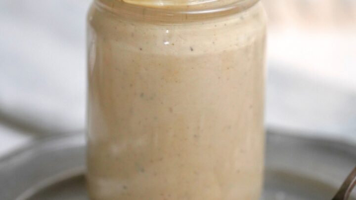 Creamy Apricot Tahini Dressing in a glass jar with a spoon