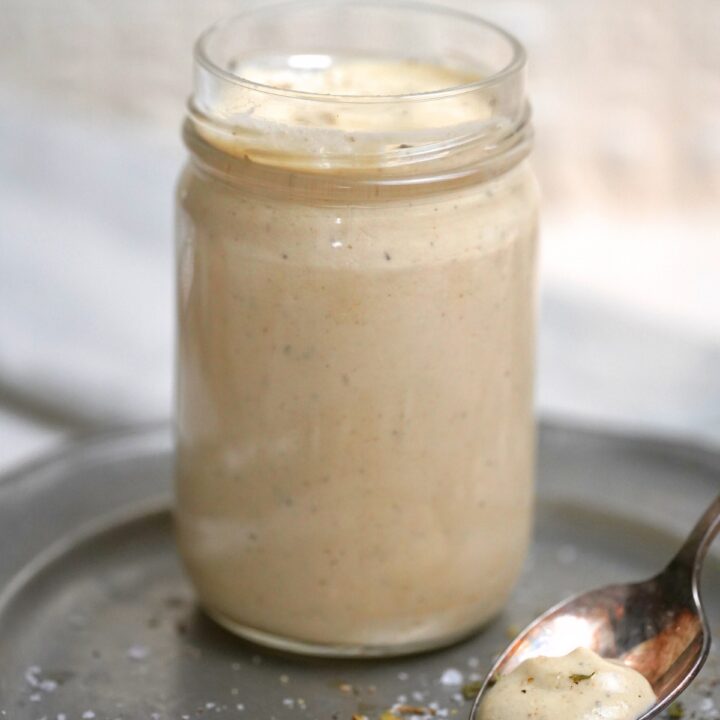 Creamy Apricot Tahini Dressing in a glass jar with a spoon