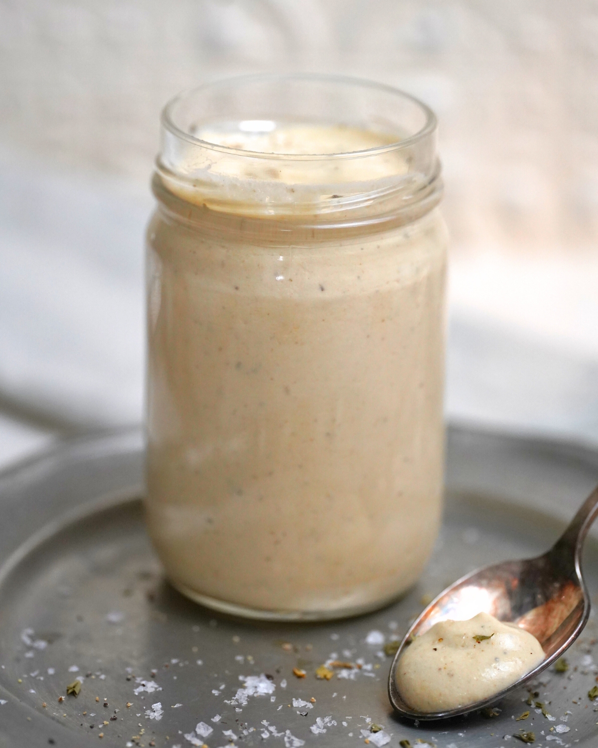 Creamy Apricot Tahini Dressing in a glass jar with a spoon