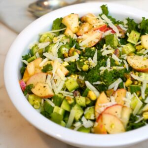 kale and apple salad in a white bowl