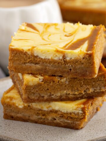 pumpkin cheesecake bars stacked on a plate