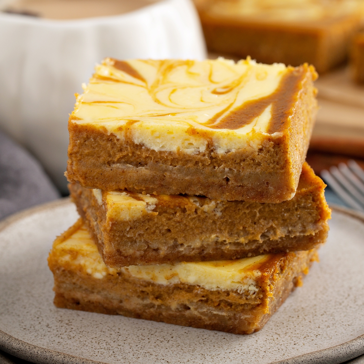 pumpkin cheesecake bars stacked on a plate