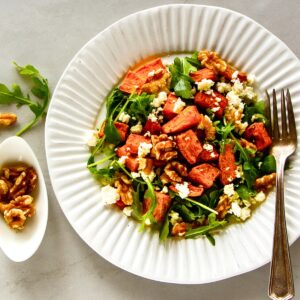 Sweet Potato and Arugula Salad with walnuts and feta cheese on a white plate