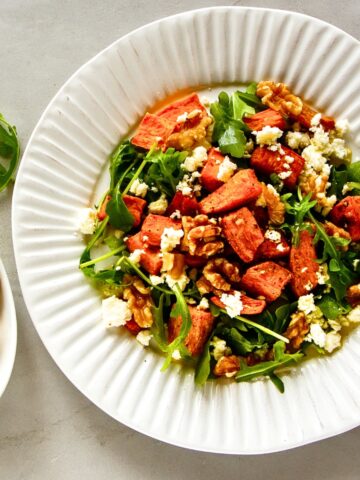 Sweet Potato and Arugula Salad with walnuts and feta cheese on a white plate