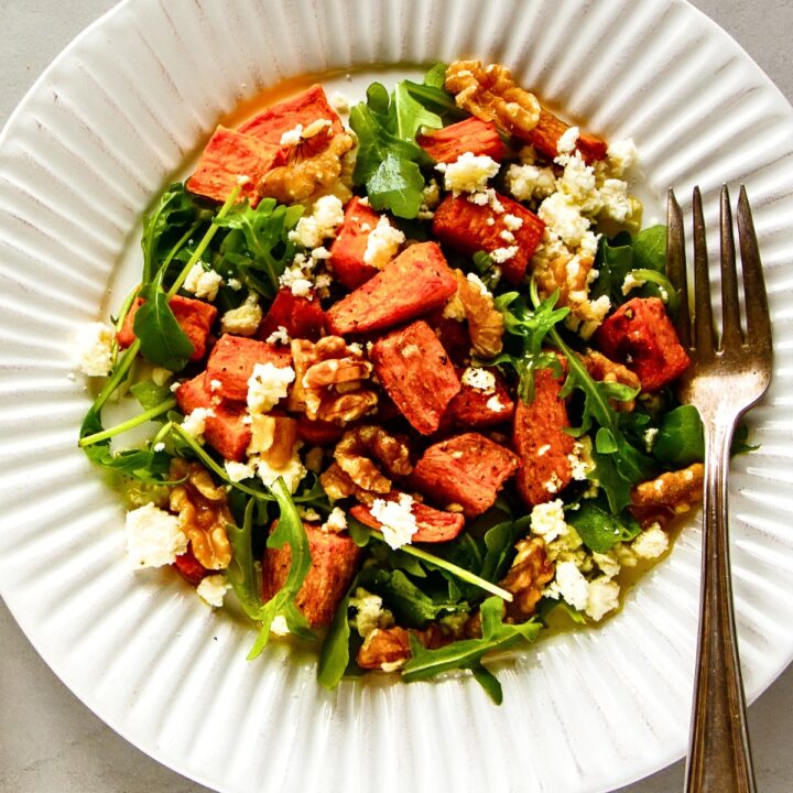 Sweet Potato and Arugula Salad with walnuts and feta cheese on a white plate